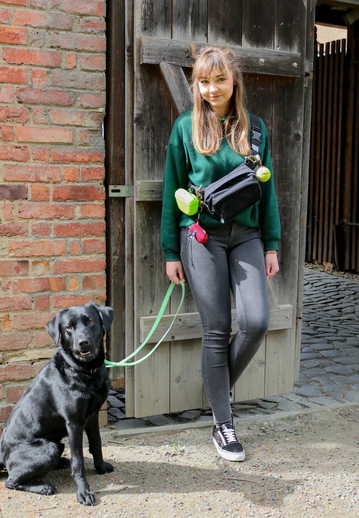 TamBe Bag ausgestattet und Cross Over vor dem Körper getragen von einer jungen Frau mit daneben sitzendem Labrador