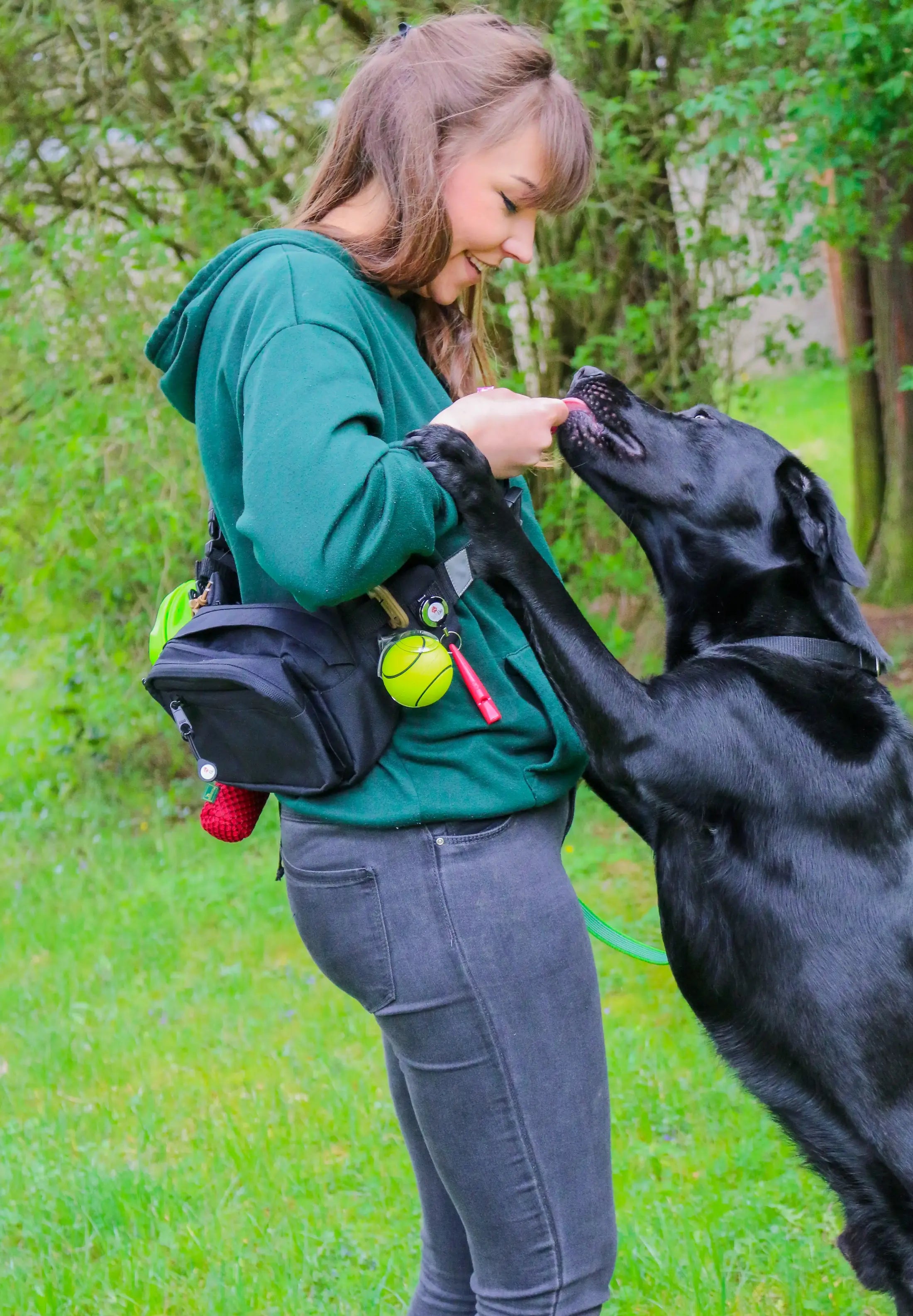 junge Frau mit TamBe Bag crossover und Labrador, der gerade an ihr hochspringt und Hand ableckt